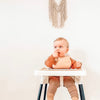 baby weaning in ikea high chair with black leg wraps